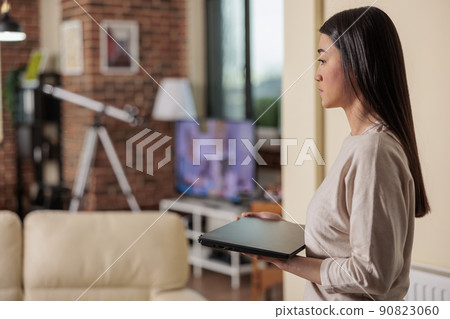 Authentic beautiful good looking asian woman walking with laptop in living room, starting to work remotelly, work from home internet web online user. freelancer in home office starting her work day 90823060