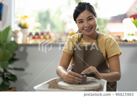 Young asian woman's hands close up, the masterful studio of ceramics works with clay on a potter's wheel. 90823983