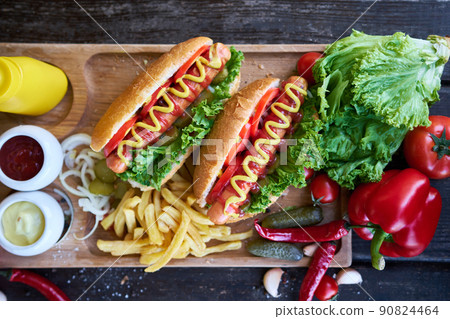 BBQ hot dog served with vegetables and French fries and sauces on wooden serving board 90824464