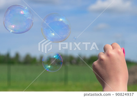 The child blows soap bubbles in nature. 90824937
