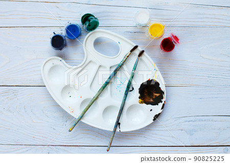 Paint palette with tassels and paints on a light blue wooden background. Flat lay art tools. Artwork workplace 90825225