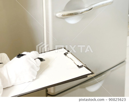 Hands of white gloves with a clipboard to assess the refrigerator Hands of white gloves with a clipboard to assess the refrigerator 90825623