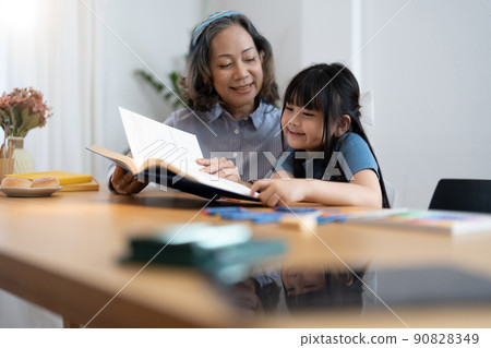 grandchild granddaughter grandma grandmother reading book girl senior. asian people. grandchild granddaughter grandma grandmother reading book girl senior. asian people. 90828349