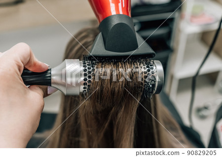 Drying blonde hair with a hair dryer and a round brush. Drying blonde hair with a hair dryer and a round brush. 90829205