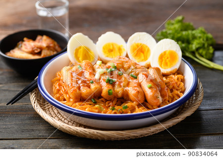 Korean spicy instant noodle with Tteokbokki, sausage and egg on wooden background 90834064