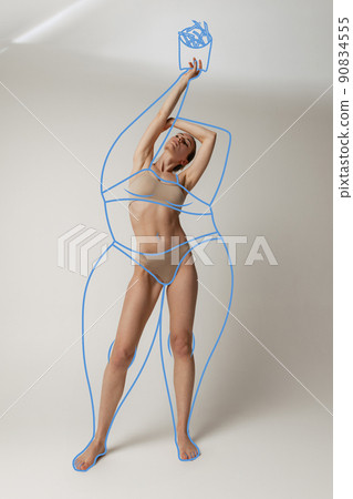 Portrait of slim woman in underwear wear posing isolated over gray studio background. Lines around body before losing weight. 90834555