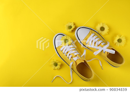 Yellow sneakers with flowers on yellow background 90834839