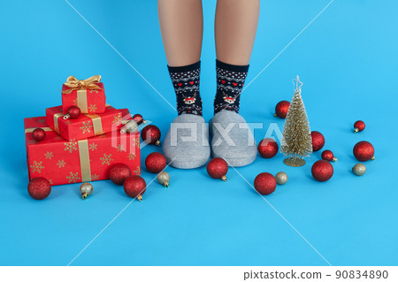 Christmas composition with female legs in Christmas socks on blue background 90834890