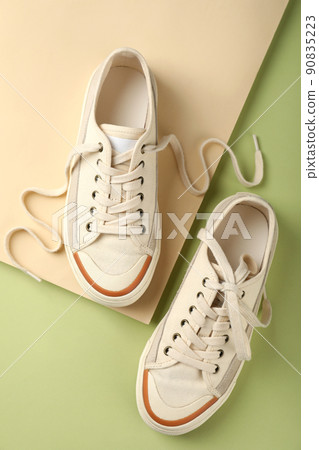 Pair of beige sneakers on two tone background Pair of beige sneakers on two tone background 90835223