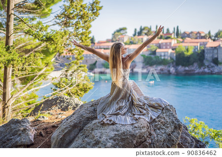Woman tourist on background of beautiful view of the island of St. Stephen, Sveti Stefan on the Budva Riviera, Budva, Montenegro. Travel to Montenegro concept Woman tourist on background of beautiful view of the island of St. Stephen, Sveti Stefan on the Budva Riviera, Budva, Montenegro. Travel to Montenegro concept 90836462