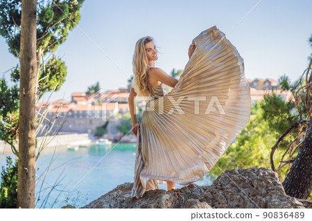Woman tourist on background of beautiful view of the island of St. Stephen, Sveti Stefan on the Budva Riviera, Budva, Montenegro. Travel to Montenegro concept Woman tourist on background of beautiful view of the island of St. Stephen, Sveti Stefan on the Budva Riviera, Budva, Montenegro. Travel to Montenegro concept 90836489