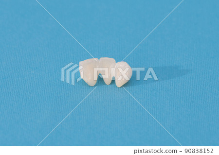 Metal free ceramic teeth implant dental crowns isolated on a blue background.  90838152