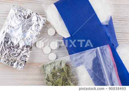 suspected drug trafficking, unknown pills, powders in the package and the foil, and like a "spice" blend, are on the table 90838493