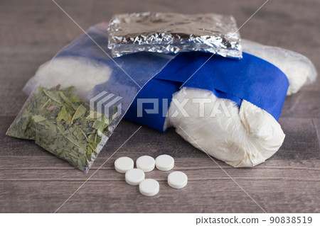 suspected drug trafficking, unknown pills, white powder in a transparent package and the foil and similar to the "spice" mixture, lay on a brown table 90838519