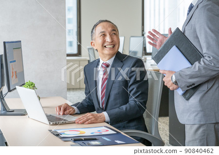 A smiling senior man talking while working on a computer 90840462