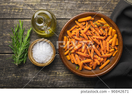 Roasted baby carrots with salt and rosemary on plate. 90842671