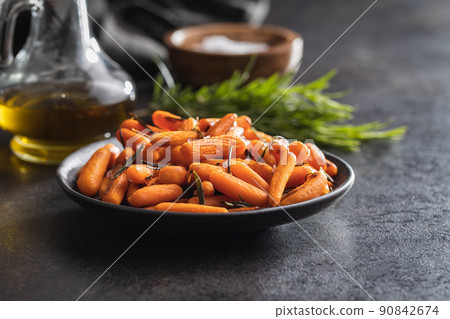 Roasted baby carrots with salt and rosemary on plate. 90842674