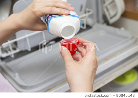 A woman's hand to put the dishwasher detergent 90843148
