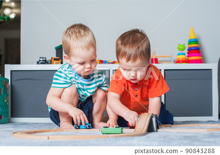 Two children boy play together with toys in interior of children's room.. 90843288