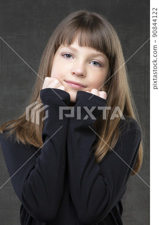 Portrait of a beautiful pensive girl of ten years old on a gray background. 90844122