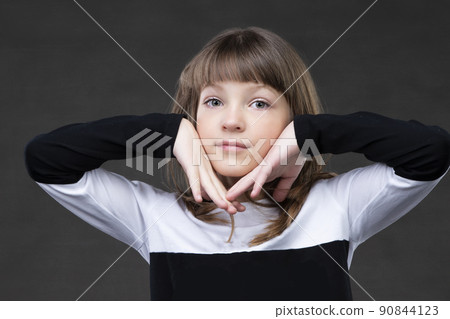 Beautiful little girl holding her face with her hands and looking at the camera. Beautiful little girl holding her face with her hands and looking at the camera. 90844123