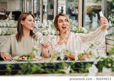 Two Women Making Selfie While Having Lunch Meeting, Female Friends Eating Salad in the Restaurant 90844653