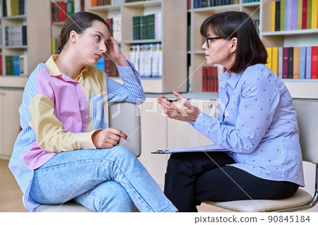 Psychologist, high school behavior counseling teenage student in library 90845184