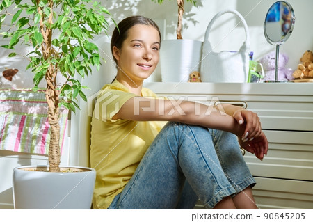Beautiful teenage girl sitting at home on floor, in sunlight 90845205