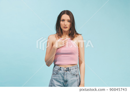 Portrait of emotional girl wearing top and denim shorts posing isolated on blue background. Concept of emotions, facial expression, youth Portrait of emotional girl wearing top and denim shorts posing isolated on blue background. Concept of emotions, facial expression, youth 90845743