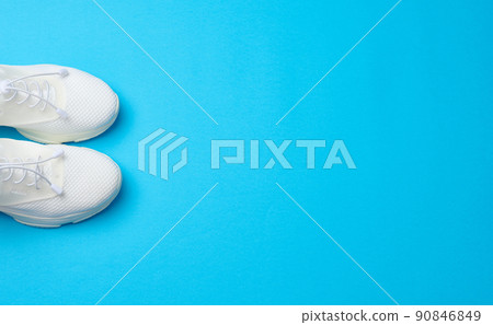 White textile sneakers on a blue background, top view 90846849