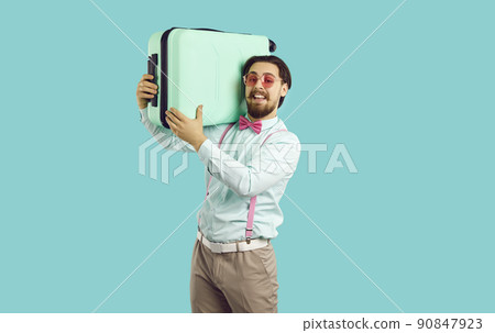 Handsome stylish young man holding suitcase on his shoulders on light blue background. Handsome stylish young man holding suitcase on his shoulders on light blue background. 90847923