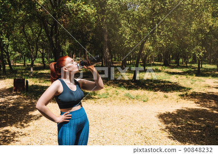 young sportswoman drinking water from a bottle after sports training. girl practising sport outdoors. health and wellness lifestyle. young sportswoman drinking water from a bottle after sports training. girl practising sport outdoors. health and wellness lifestyle. 90848232
