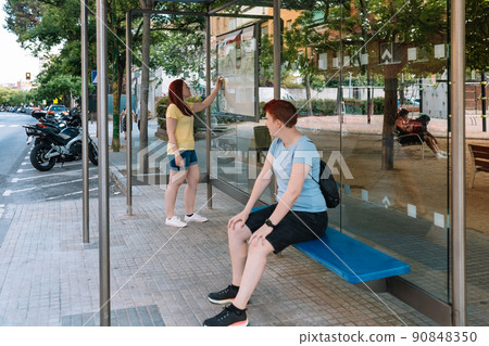 two young girls waiting for the city bus at the bus stop. friends going out to have fun in the city. concept of friendship 90848350