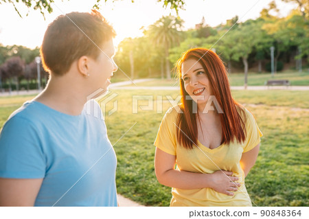 side image two great friends chatting and strolling happily, in a city public park at sunset. young girls enjoying the summer outdoors. concept of friendship and companionship. 90848364