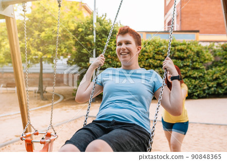 friends young women playing like children in a public park with a swing. girls having fun in the city. concept of friendship and companionship. 90848365