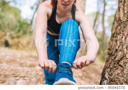 detail of the hands of a young girl athlete tying her trainers outside in a public park. sportswoman doing training exercises. health and wellness lifestyle. detail of the hands of a young girl athlete tying her trainers outside in a public park. sportswoman doing training exercises. health and wellness lifestyle. 90848378