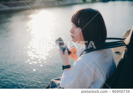 Schoolgirl in uniform with a guitar and smartphone and the city 90848736