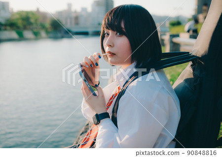 穿著制服的女學生有吉他和智能手機和城市 90848816