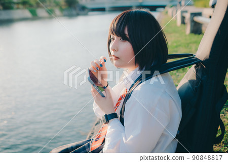 穿著制服的女學生有吉他和智能手機和城市 穿著制服的女學生有吉他和智能手機和城市 90848817