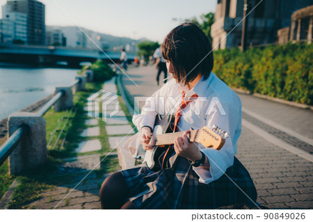 Schoolgirl in uniform playing the guitar and the city Schoolgirl in uniform playing the guitar and the city 90849026