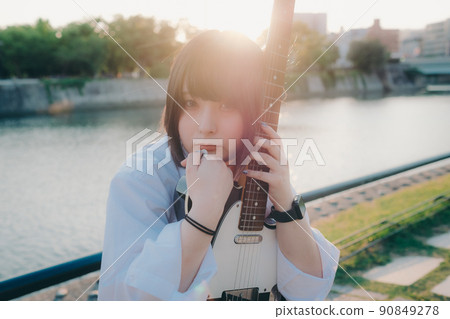 Schoolgirl in uniform with a guitar and the city 90849278