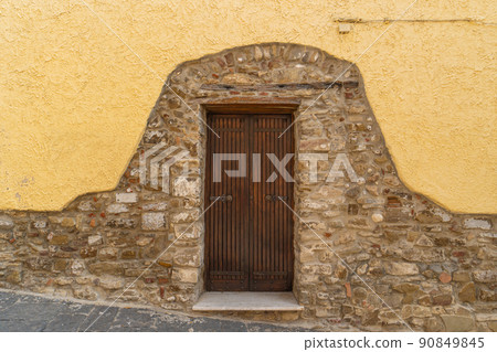 A partially plastered stone wall with a door A partially plastered stone wall with a door 90849845