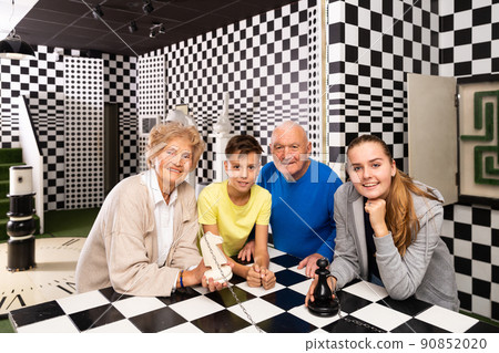 Grandparents with grandchildren are satisfied after visit of escape room stylized under chess board 90852020