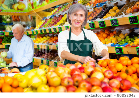 Female supermarket worker stacking fruits on shelf in sales room 90852042