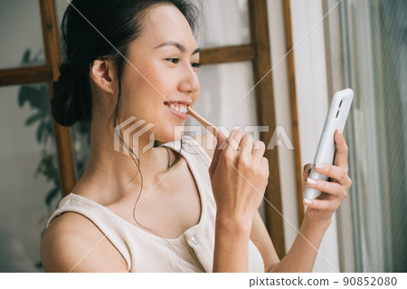 Women brushing their teeth while looking at their smartphones ・ Women using bamboo toothbrushes Women brushing their teeth while looking at their smartphones ・ Women using bamboo toothbrushes 90852080