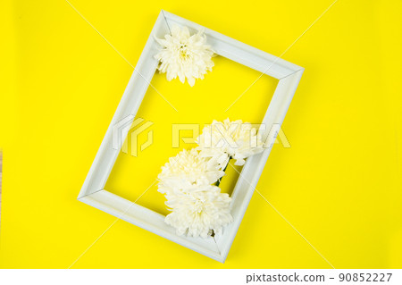 A white frame with three white flowers on a bright yellow background inside. High quality photo A white frame with three white flowers on a bright yellow background inside. High quality photo 90852227