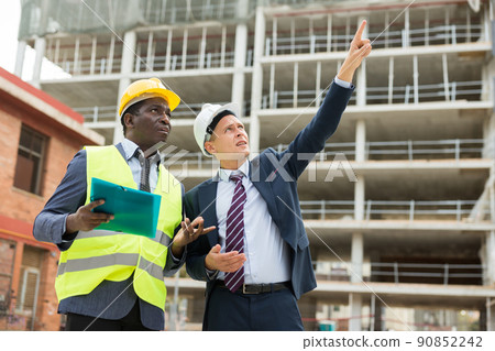 Foreman showing builder something at the construction site by pointing hand 90852242