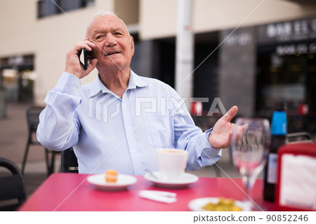 Senior man talking on phone in outdoor cafe 90852246