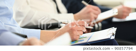 Group of business people sitting in audience with documents with charts closeup 90857794