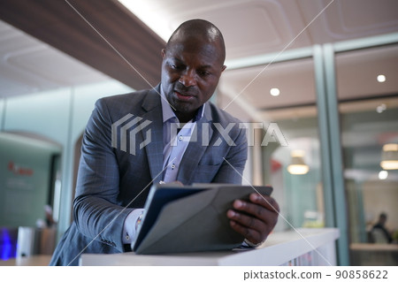 Portrai of African American businessman using laptop of mobile device in modern office. Portrai of African American businessman using laptop of mobile device in modern office. 90858622